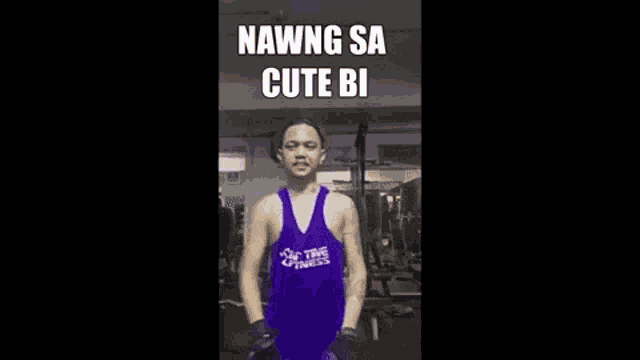 a man in a purple tank top is standing in a gym with a meme .