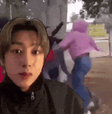 a man in a black jacket is standing in front of a woman in a pink hoodie .