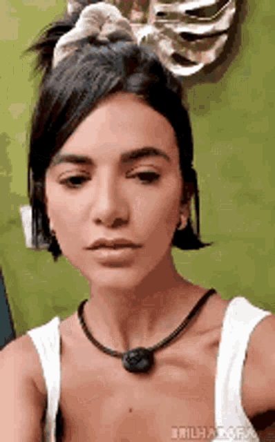 the woman is wearing a white tank top and a necklace .