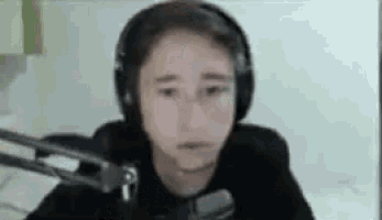 a boy wearing headphones is sitting in front of a microphone .