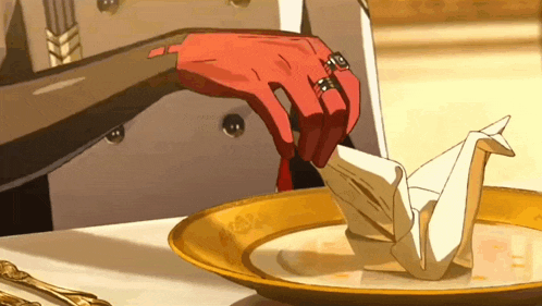 a person with a ring on their finger is folding an origami bird