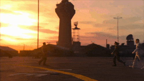 a group of people are walking in front of a tower at sunset