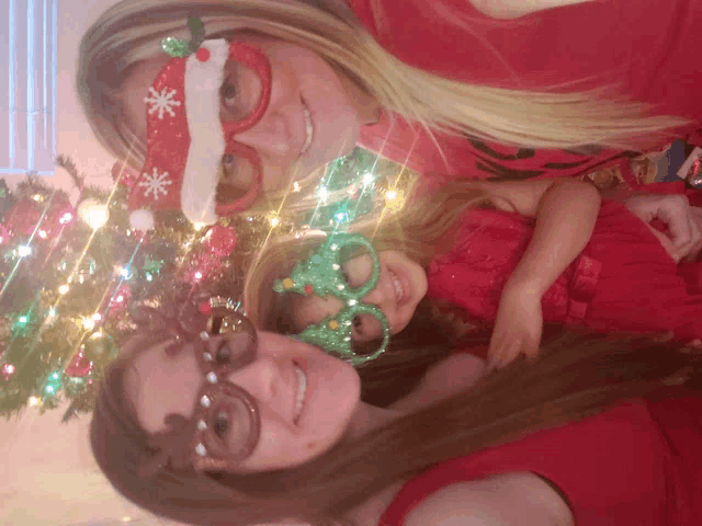 two women and a little girl wearing santa hats and glasses