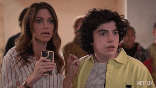 a woman holds a cell phone next to a boy who is wearing a yellow shirt that says netflix on it