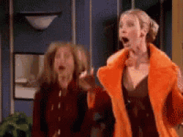 two women are standing next to each other with their mouths open and one is wearing an orange fur coat .