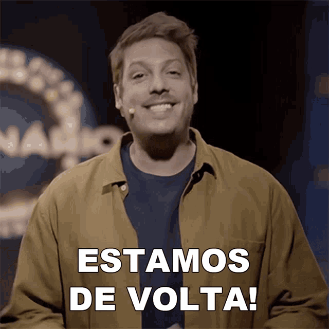a man stands in front of a microphone and says estamos de volta