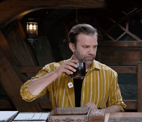 a man in a yellow striped shirt is drinking from a black cup
