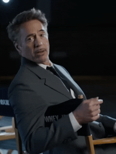 a man in a suit and tie is sitting in a director 's chair that says pascal on it