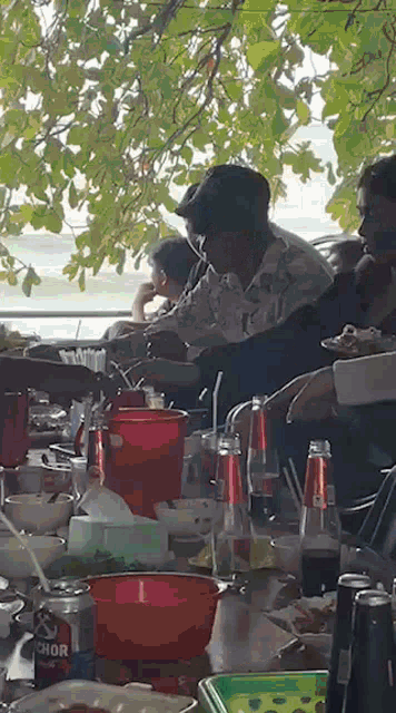 a group of people sitting at a table with a can of anchor beer on it .