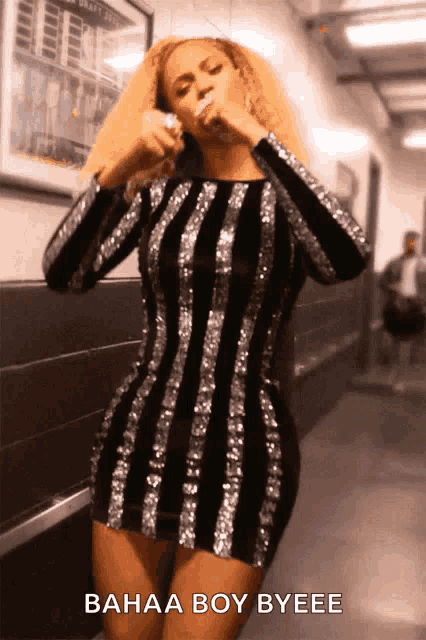 a woman in a black and silver striped dress is standing in a hallway and says bahaa boy byeee