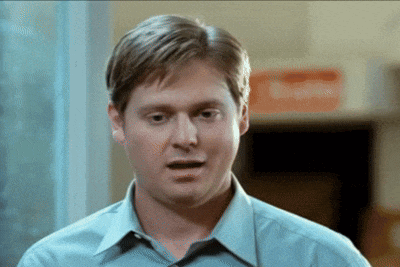 a man in a blue shirt is standing in front of a red exit sign