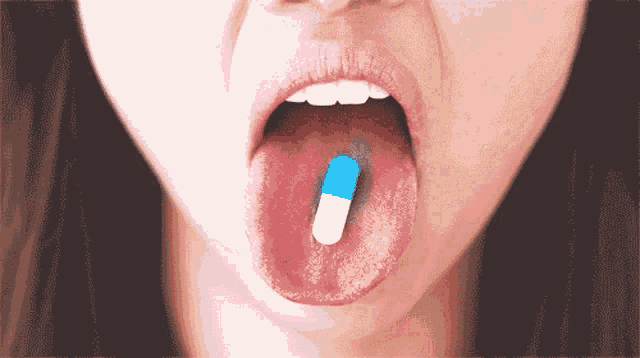 a woman is sticking out her tongue with a blue and white pill in her mouth