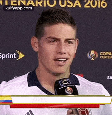 a soccer player is talking into a microphone while wearing a white shirt .