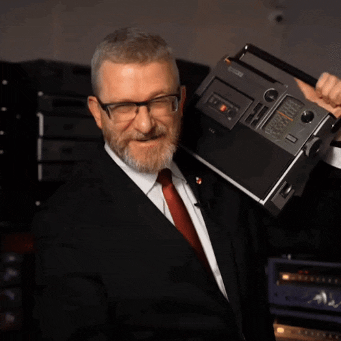 a man in a suit and tie holds a sony radio