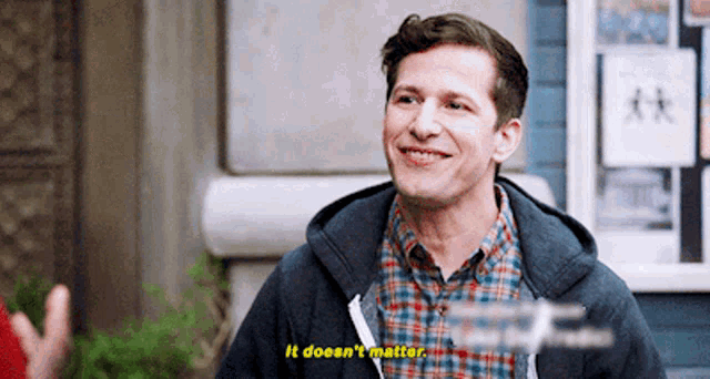 a man wearing a plaid shirt and a hoodie is smiling and says it does n't matter .