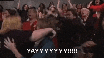 a crowd of people are standing in a room with their arms in the air and yelling .