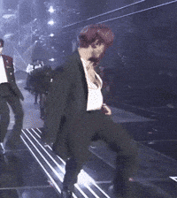 a man in a suit is dancing on a stage in front of a crowd