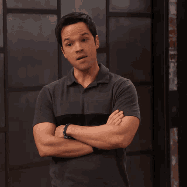 a man with his arms crossed is wearing a gray shirt
