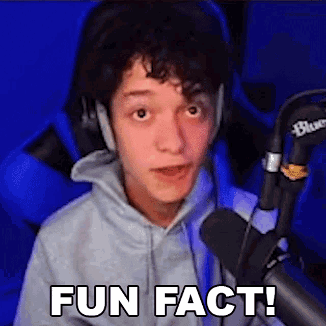a young man wearing headphones is sitting in front of a microphone and saying `` fun fact '' .