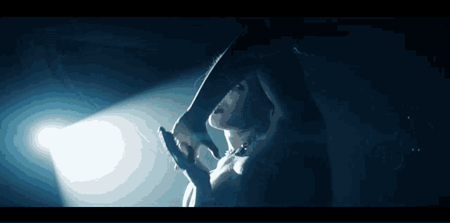 a woman is standing in a dark room with a spotlight shining on her