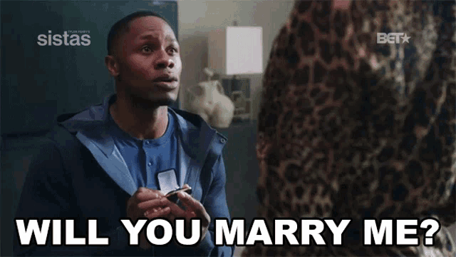 a man is asking a woman if she will marry him and bet is behind him