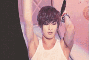 a young man in a white tank top is holding a pair of scissors .