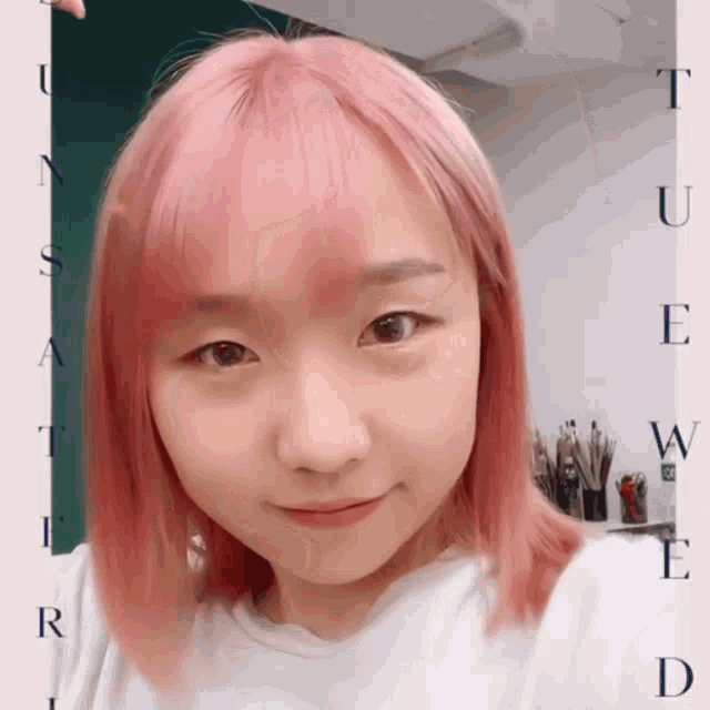 a woman with pink hair is smiling in front of a sign that says tue