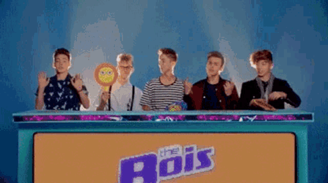 a group of boys are sitting at a table with a sign that says " the bois "