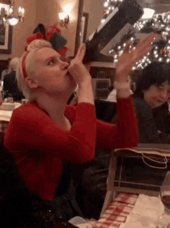 a woman in a red shirt is drinking from a wine bottle