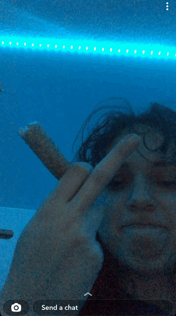 a person holding a cigarette in front of their face with a send a chat button below them