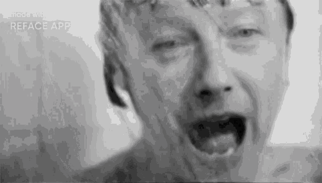 a black and white photo of a man with his mouth open taking a shower .