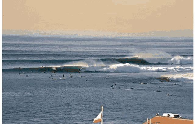 a large body of water filled with surfers and a flag in the foreground