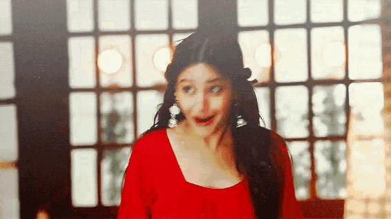 a woman in a red dress is standing in front of a window .