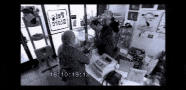 a black and white photo of people in a store with a time stamp of 16:10 19:12