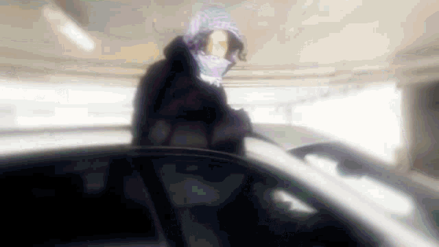 a person wearing a hooded jacket and a scarf is standing next to a car