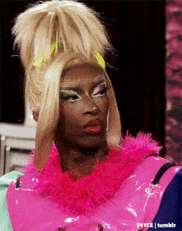 a drag queen is wearing a pink jacket and a pink feathered collar