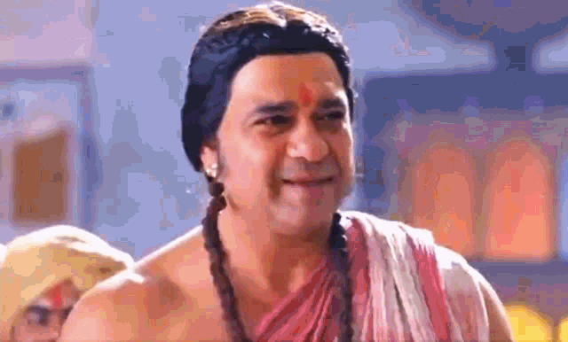 a man is wearing a wig and a towel and smiling .