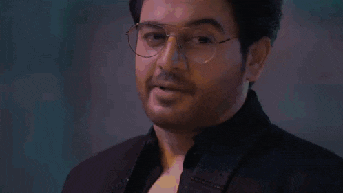 a man wearing glasses and a black jacket is looking at the camera .