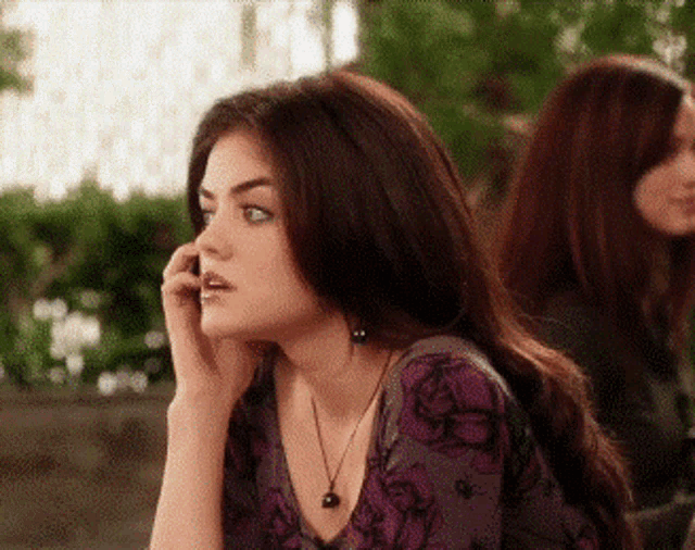 a woman in a purple shirt is talking on a cellphone