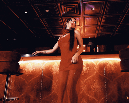 a woman in a red dress is standing on a bar