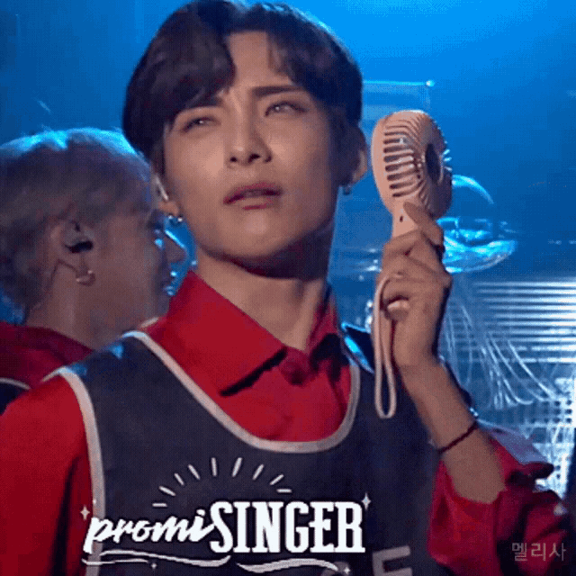 a man in a red shirt is holding a fan and the word promisinger is on his vest