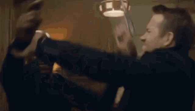 two men are fighting each other in a room .