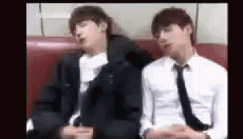 two men in suits and ties are sitting on a couch .