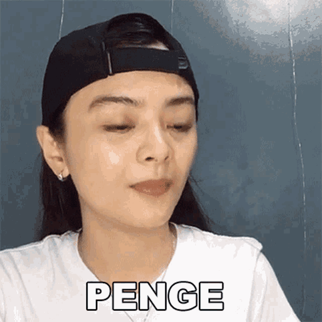 a woman wearing a baseball cap and a white shirt with the word penge on her face