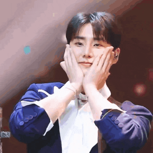 a man in a blue jacket is making a heart shape with his hands