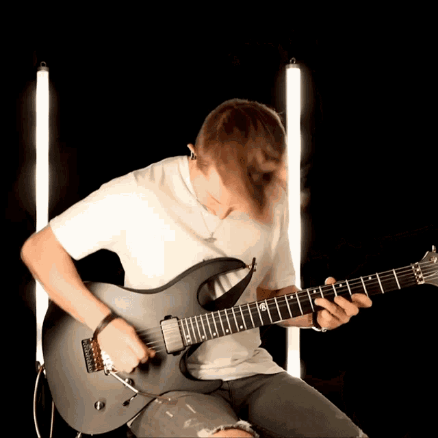 a man in a white shirt is playing a guitar with the letter r on the neck