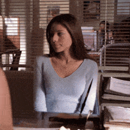 a woman in a light blue sweater is sitting at a desk