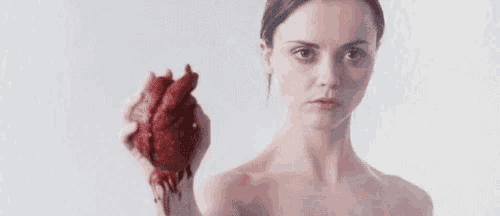 a woman is holding a bloody heart in her hands .
