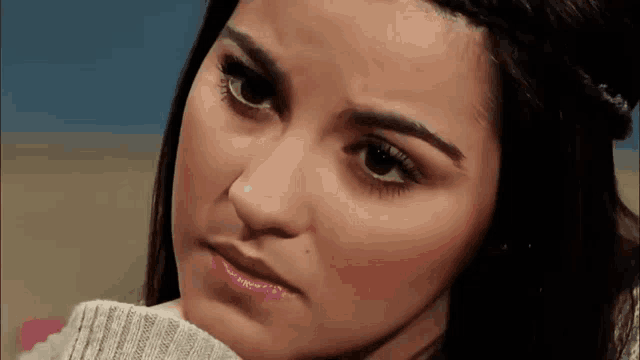 a close up of a woman wearing a grey sweater
