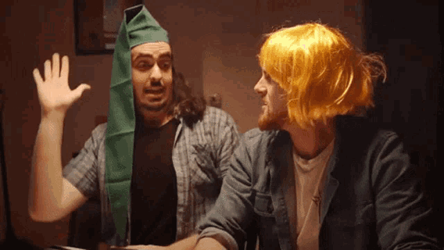 a man wearing a green hat is talking to another man with yellow hair
